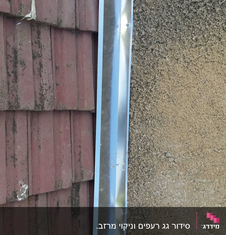 רעפים אדומים עם איטום לבן ליד קיר בטון